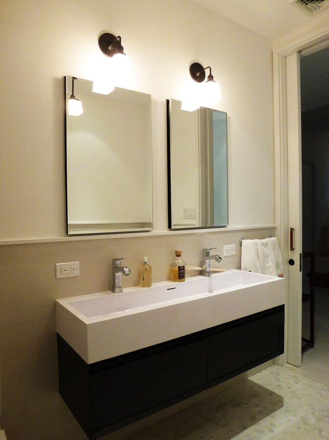 Brightly lit bathroom with 2 mirrors and a double vanity sink